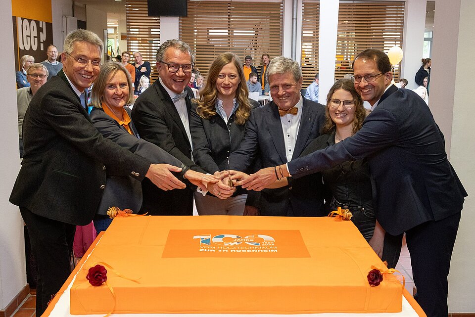 Das Bild zeigt eine Gruppe von Personen vor der Geburtstagstorte beim Tag der offenen Tür.