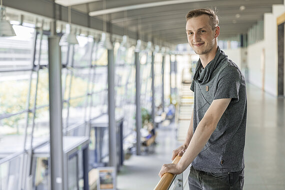 Student stützt sich mit Armen an Geländer ab