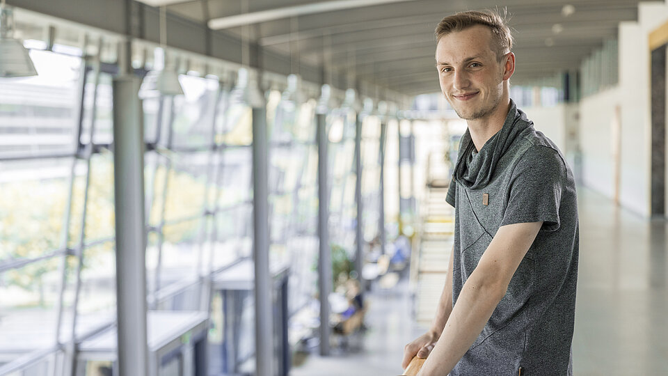 Student stützt sich mit Armen an Geländer ab