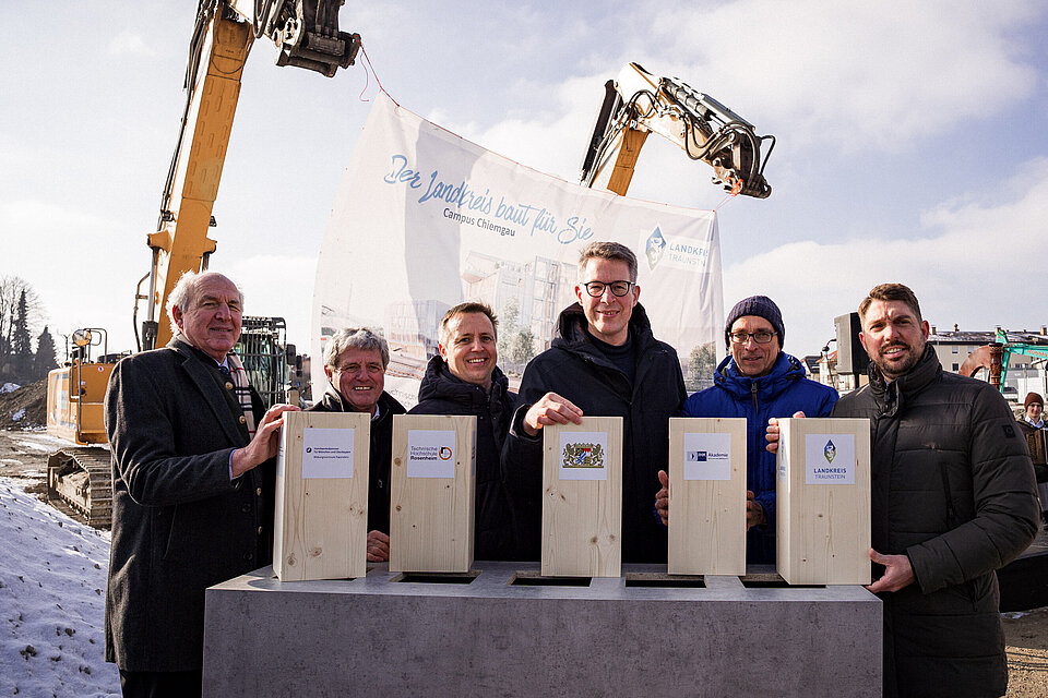 Das Bild zeigt eine Gruppe von Personen auf der Baustelle für den neuen Campus Chiemgau.