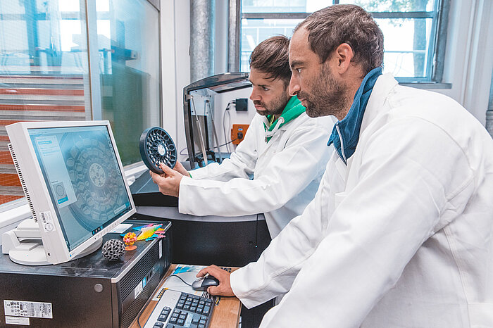 Das Bild zeigt Professor Fabian Riß zusammen mit einem Mitarbeiter im Labor für Additive Fertigung.